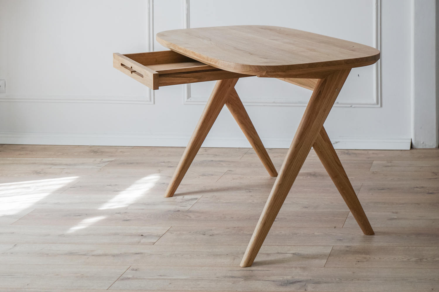 Kunsst wooden writing desk can successfully be used as  for makeup desk in bedroom or even wooden office desk, wooden desk with drawers with drawer under desk or solid oak desk for home office. Angled view of writing desk with drawer opened.