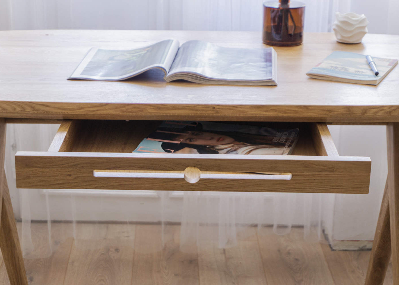 Kunsst solid wood desk for home office can be used as wooden office desk, wooden desk with drawers for makeup or even desk in bedroom with drawer under desk or solid oak desk for home office. Oak wooden desk standing on wooden flor in front of window