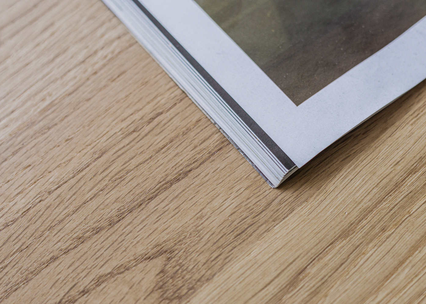 Kunsst- solid oak desk top with drawer under wooden desk . Detail on magazine laying on kunsst desk for home office or bedroom