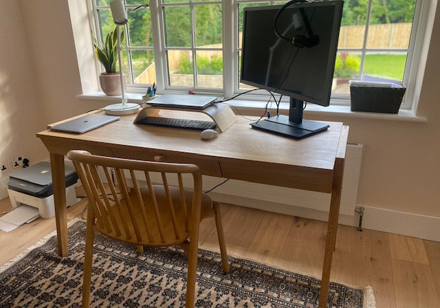 Oak desk with drawer in a home office setup in front of window