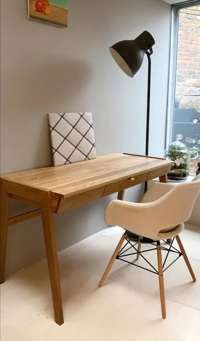 wooden desk with drawer in bright home office with window, chair and white carpet on floor