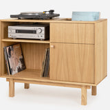 A solid oak vinyl record cabinet with a turntable on top and a small shelf with a framed picture and a decorative item.
