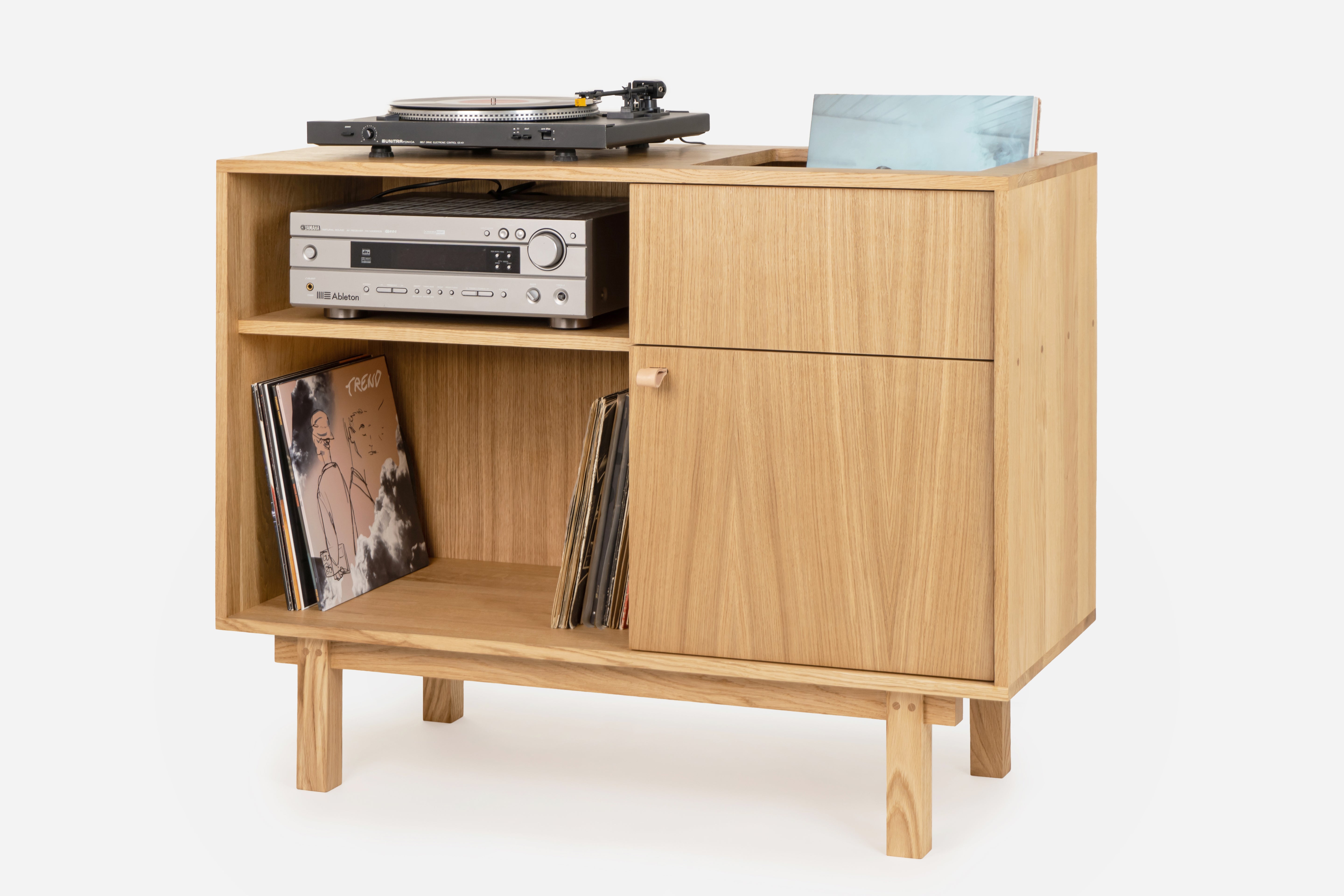 A solid oak vinyl record cabinet with a turntable on top and a small shelf with a framed picture and a decorative item.
