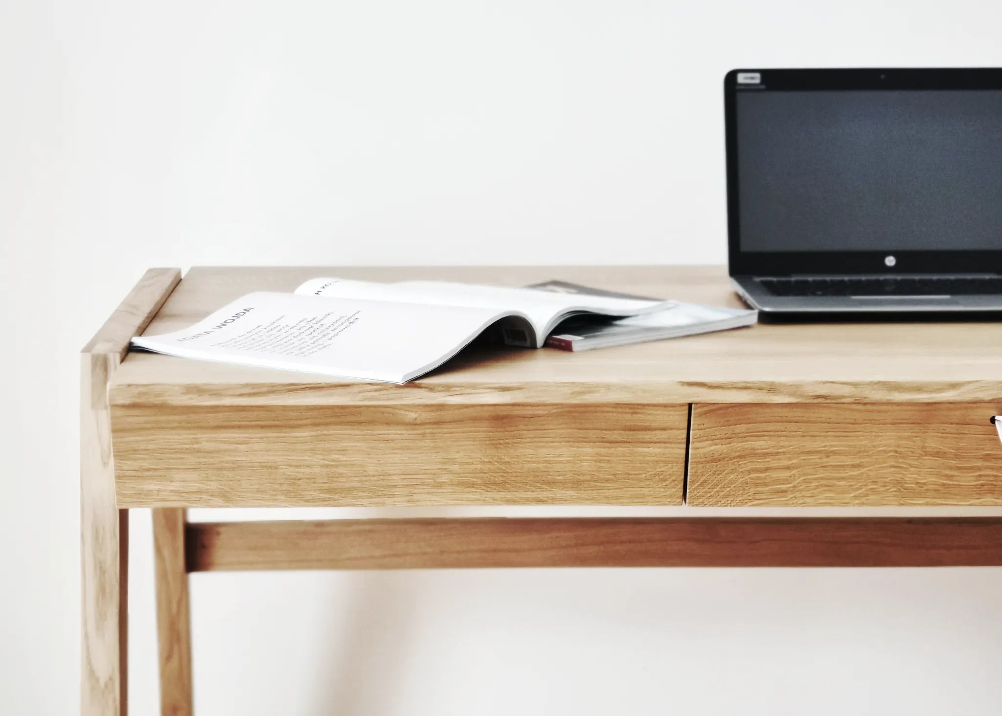 Front view of handmade wood desk with drawer with a laptop and open book on a white background