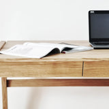Front view of handmade wood desk with drawer with a laptop and open book on a white background