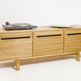 A wooden storage cabinet with a record player on top and a sheet of music on the side.