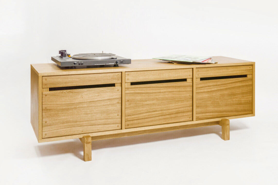 A wooden storage cabinet with a record player on top and a sheet of music on the side.