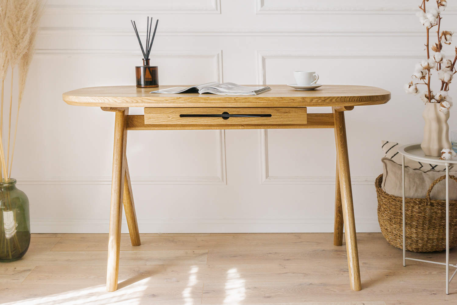 Can successfully be used as  for makeup desk in bedroom or even wooden office desk, wooden desk with drawers with drawer under desk or solid oak desk for home office also known as writing desk. Front view of handmade furniture standing on wooden floor with the magazine on top and cup of coffee. 