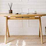 Can successfully be used as  for makeup desk in bedroom or even wooden office desk, wooden desk with drawers with drawer under desk or solid oak desk for home office also known as writing desk. Front view of handmade furniture standing on wooden floor with the magazine on top and cup of coffee. 