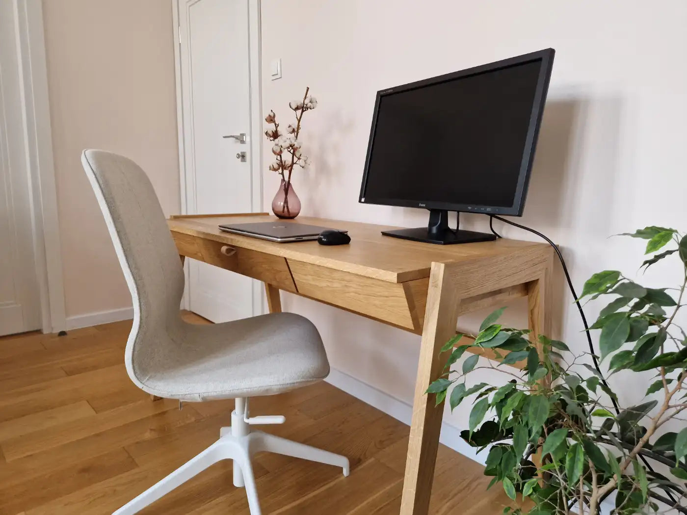 Monitor and laptop standing on wooden desk with drawer made of solid oak
