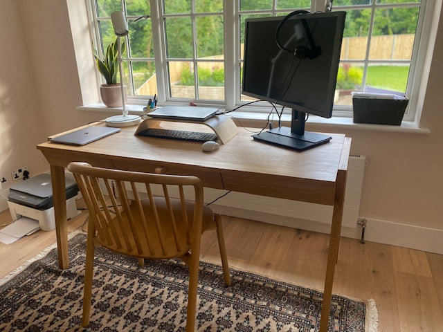 Home office setup with a solid oak desk with drawer, chair, computer monitor, and keyboard.
