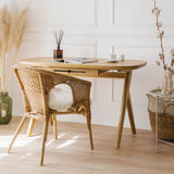 Elegant solid wood vintage desk for a vanity with wicker chair and decorative items, standing on a wooden floor in a classic style room with wall mouldings.