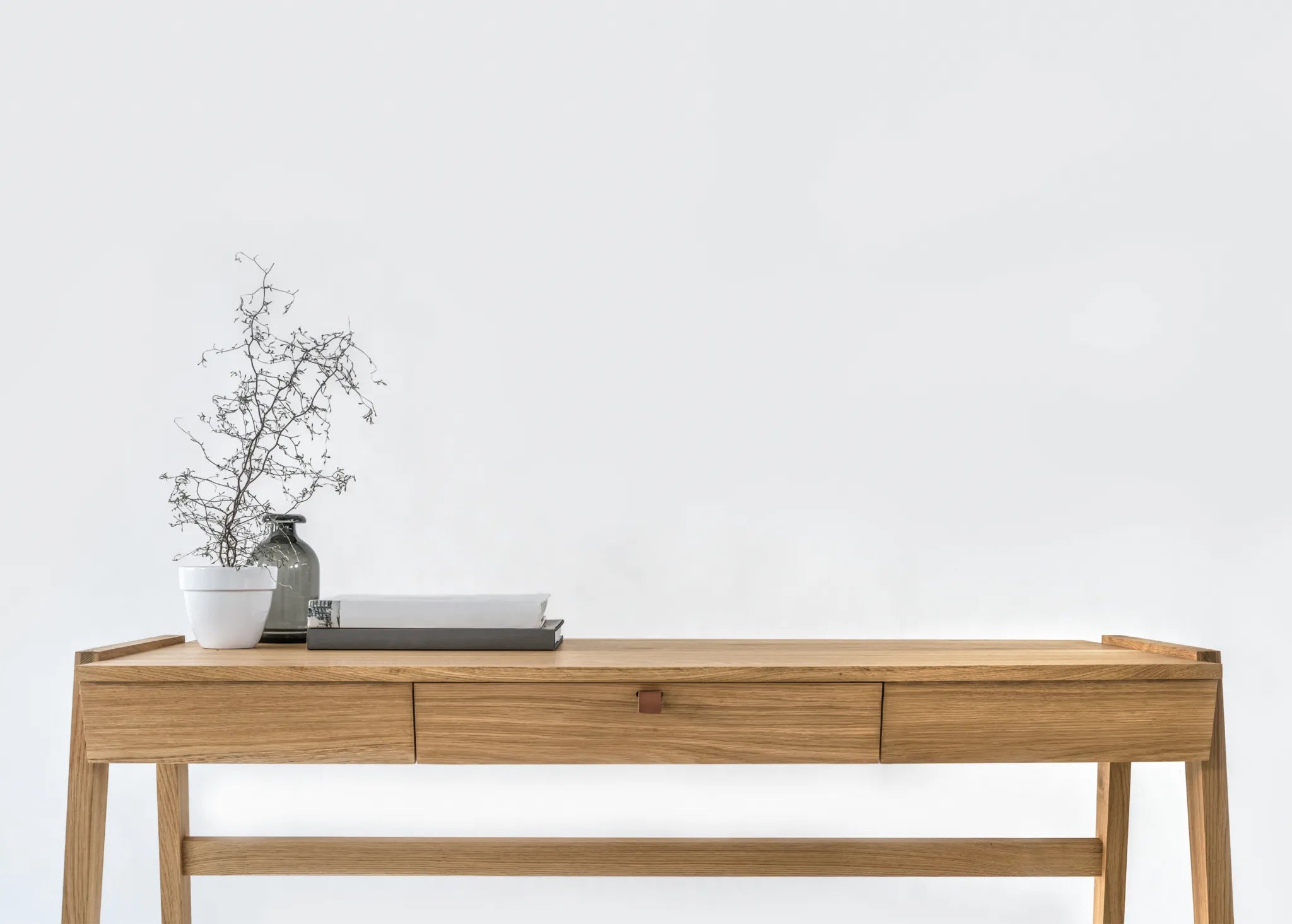 Front view of solid wood desk with drawer, crafted from premium oak with a vase and branches on a white background
