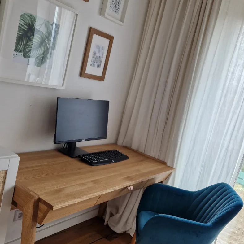 Wooden desk with drawer, blue chair, and framed artwork on the wall in home office setup